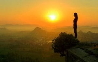 a woman's silhouette at a sunlit mountaintop...